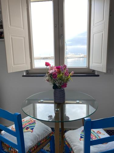 a glass table with a vase of flowers and two chairs at La Baia di Napoli in Capri