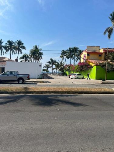 a street with cars parked in a parking lot with palm trees at Habitación 18 a unos pasos de la playa Las Brisas in Manzanillo