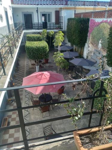a patio with tables and a pink umbrella at Hotel Marmoy in Cholula