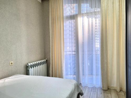 a bedroom with a bed and a large window at Sea apartment baTumi in Batumi