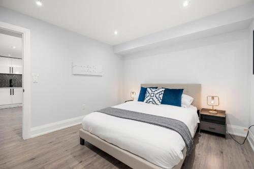 a white bedroom with a large bed with blue pillows at Modern Home Pool Still Open Two Fire Pits Free Parking Game Room in Toronto
