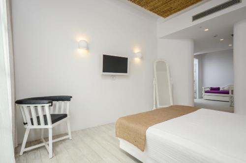a white bedroom with a bed and a chair at Thomais Studios in Naxos Chora