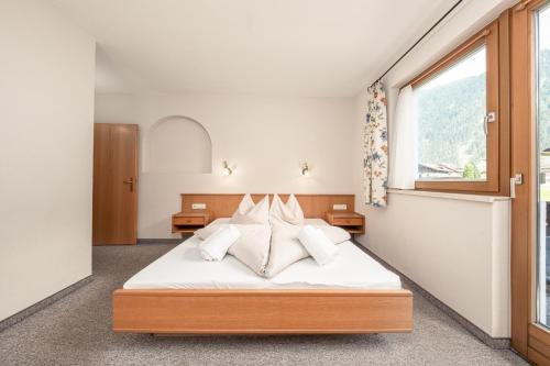 a bedroom with a bed with white sheets and pillows at Apartments Alpina in Mayrhofen