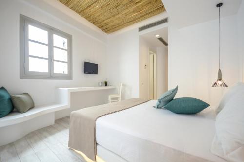 a white bedroom with a bed and a window at Thomais Studios in Naxos Chora