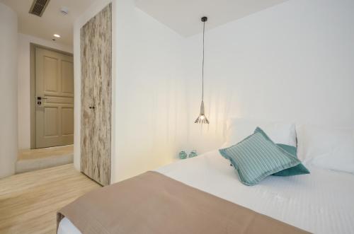 a bedroom with a white bed with a blue pillow at Thomais Studios in Naxos Chora
