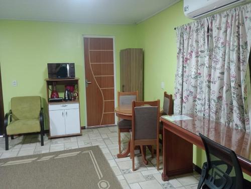Habitación con escritorio, mesa y sillas. en Refúgio familiar, en Canela