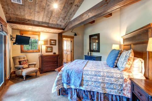 ein Schlafzimmer mit einem Bett, einem Fernseher und einem Stuhl in der Unterkunft KBM Resorts Deer Valley Penthouse On Citywide shuttle bus Hot Tub Pool Table Shuffleboard PRH-685 in Park City