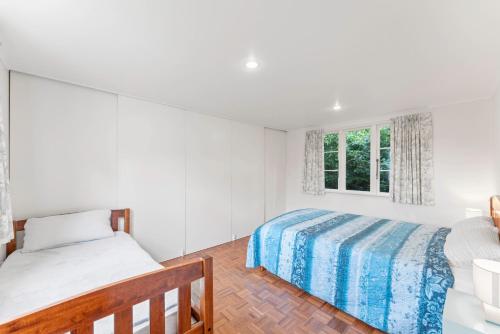 a white bedroom with two beds and a window at Tongariro Base Camp - Turangi Holiday Home in Turangi