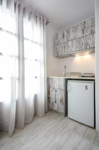 a kitchen with white curtains and a white refrigerator at Thomais Studios in Naxos Chora