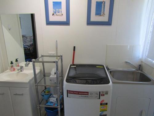 a small bathroom with a sink and a machine at Honeysuckle Lodge in Cowes