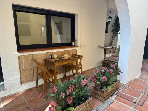 a table and chairs on a patio with flowers at Cabopino Beach & Marina Apartment in Marbella