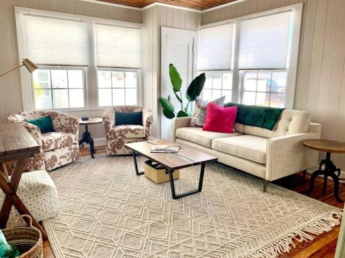 Una sala de estar con un sofá y sillas y ventanas. en Be A Nomad - Beach Bliss - House Perfect for Grps, en Jacksonville Beach