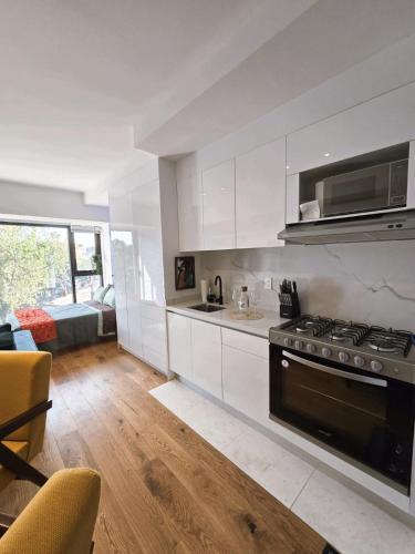 a kitchen with white cabinets and a stove top oven at Ultimate Getaway in Luxe Studio in Mexico City