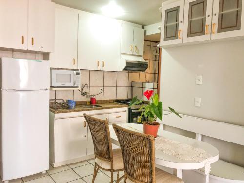 a kitchen with a table and a white refrigerator at Jurerê Internacional - Apartamento no Open Shopping in Florianópolis