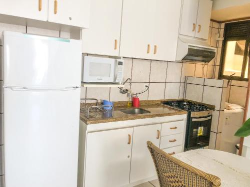 a kitchen with white cabinets and a white refrigerator at Jurerê Internacional - Apartamento no Open Shopping in Florianópolis