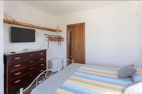 a bedroom with a bed and a dresser with a television at Trappito Stracca Agriturismo in Alezio