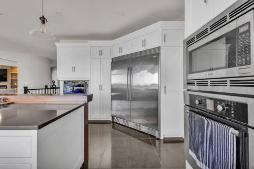 a kitchen with white cabinets and a stainless steel refrigerator at Private Farmhouse Getaway with hot tub in Waterloo