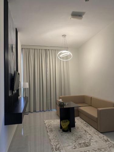a living room with a couch and a table and a television at Al Zahra Hotel Apartments Ras Al Khaimah in Ras al Khaimah