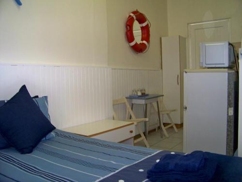 a bedroom with a bed and a table and a refrigerator at Jetty Self-Catering in Swakopmund