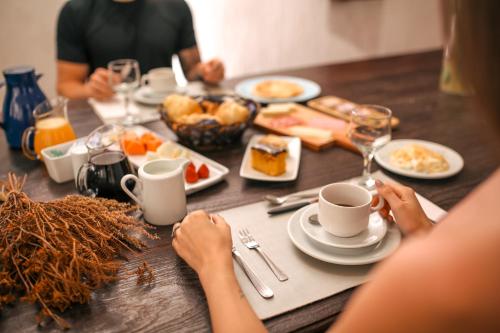 a table topped with plates of food and cups of coffee at Mosteiro Hotel de Charme próximo ao Vale dos Vinhedos in Garibaldi