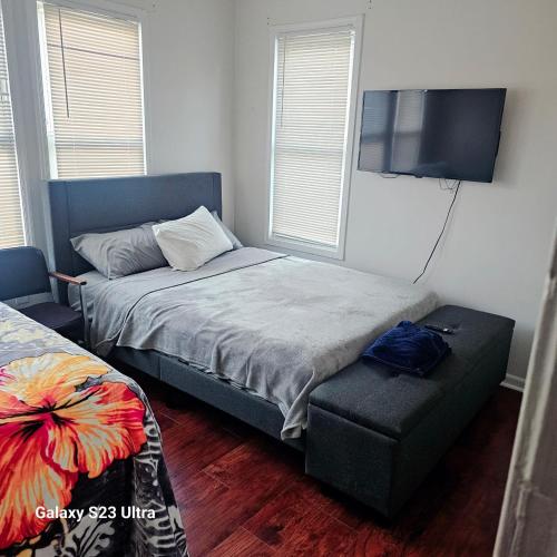 a bedroom with a bed and a chair and a flat screen tv at Divine Villa & Resorts Guest House - 283 Lehigh Ave in Newark