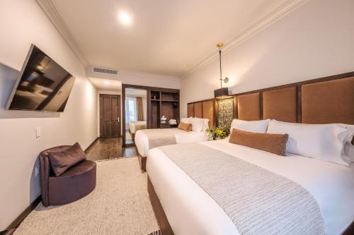 a hotel room with two beds and a chair at Casa Kloster Hotel Boutique in Guanajuato
