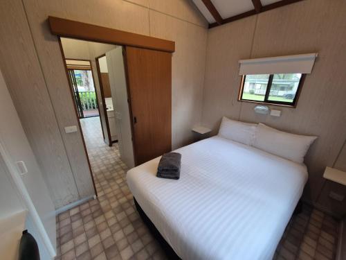 a bedroom with a white bed with a black bag on it at Eagle Point Caravan Park in Eagle Point