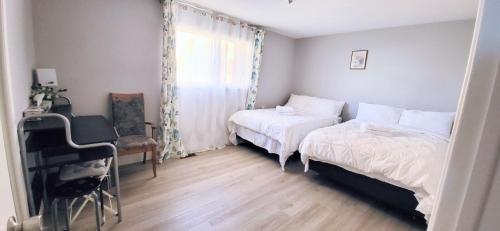 索罗尔德Cozy Home Close to Attractions in Niagara Falls的一间卧室，有两张床、一张书桌和一扇窗户
