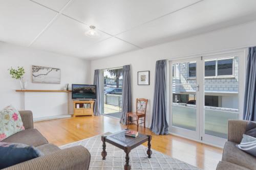 a living room with a couch and a table at Downtown Cosy Cottage in Mount Maunganui