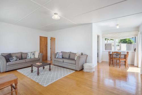 a living room with two couches and a table at Downtown Cosy Cottage in Mount Maunganui