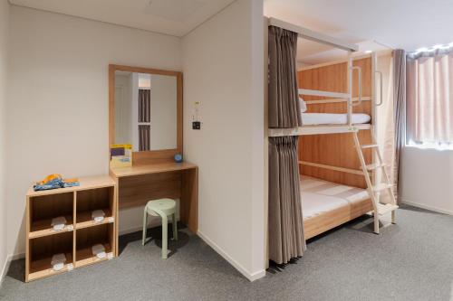 a bedroom with bunk beds and a desk and a mirror at Mangrove Jeju City in Jeju