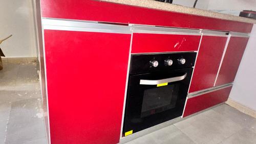a red cabinet with a black oven in a kitchen at Mini Studio de Luxe in Thiès