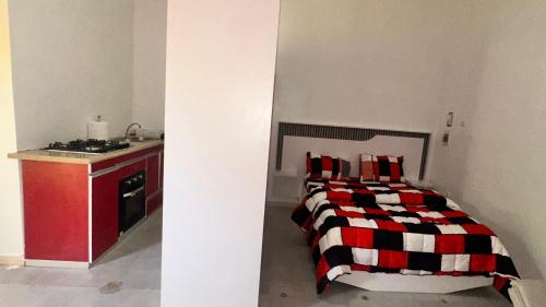 a bedroom with a bed with a red and black blanket at Mini Studio de Luxe in Thiès
