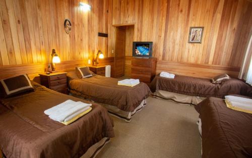 a room with three beds and a tv in it at Cabañas Antuken - Piscina Cubierta - in San Martín de los Andes