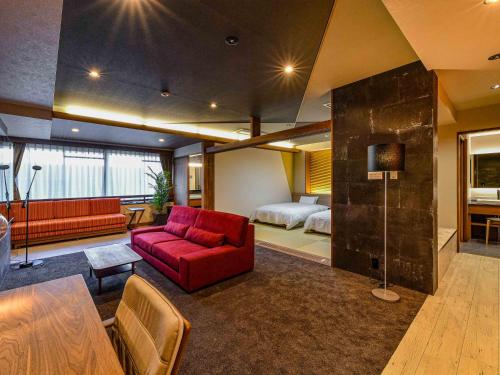 a living room with a red couch and a bed at Hokuriku Fukui Awara Onsen Mimatsu in Awara