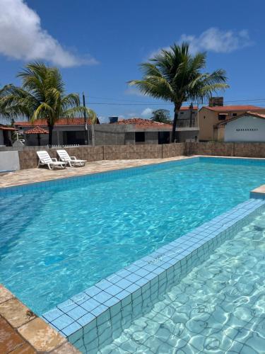 a swimming pool with blue water and palm trees at Chalé Park Mar II Casa c piscina,São José,Maragogi in São José da Coroa Grande