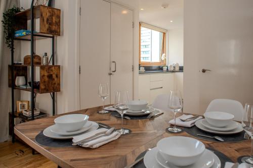 a dining room table with white dishes and wine glasses at Luxury cosy apartment with stunning London skyline views! in London