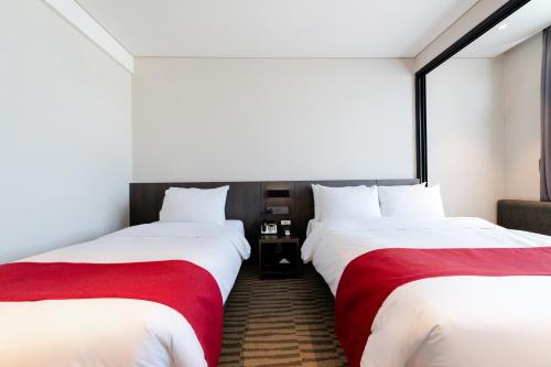 two beds in a hotel room with white and red sheets at Best Western Plus Jeonju in Jeonju
