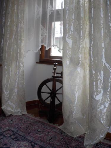 a window with white curtains and a wheel next to a bed at Hotel Kriváň in Kysucké Nové Mesto