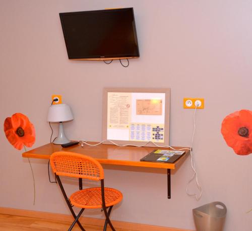 a desk with a computer on a wall with red flowers at Logis - Hotel & Restaurant La Corne d 'Abondance in Bourgthéroulde