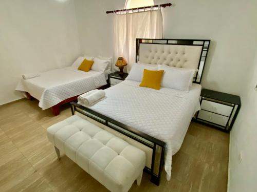 a bedroom with two beds and a bench in it at Casa Tipo Villa, Piscina, Playas De RSJ a 4 min in Río San Juan