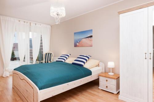 コウォブジェクにあるSunny Apartments Jantarの白いベッドルーム(青いシーツと枕付きのベッド1台付)