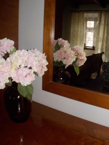 a vase filled with pink flowers in front of a mirror at Hotel Kriváň in Kysucké Nové Mesto