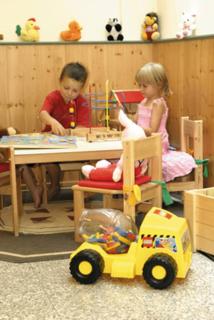 two children sitting at a table with a toy truck at Appartementhaus Alpenrose in Wallgau
