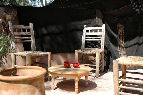 two chairs and a table with two red bowls on it at La Ferme Berbere Adult only in El Harkat