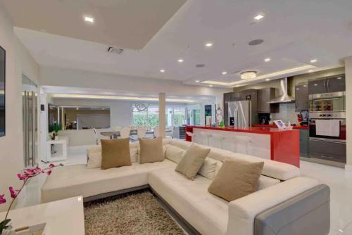 a living room with a white couch and a kitchen at The Palms Villa with Cinema, Game Table, Pool, Jacuzzi , Giant Chess, 8 Beds in Miami