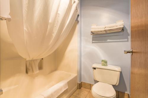 a bathroom with a toilet and a shower with towels at Governors Inn a Travelodge by Wyndham in Pierre