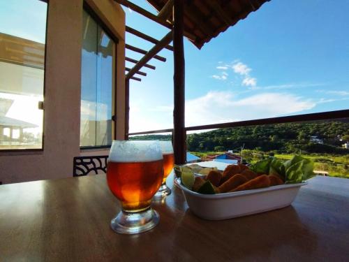 a glass of beer and a bowl of fruit on a table at Chalé Jenipapo in Serra do Cipo
