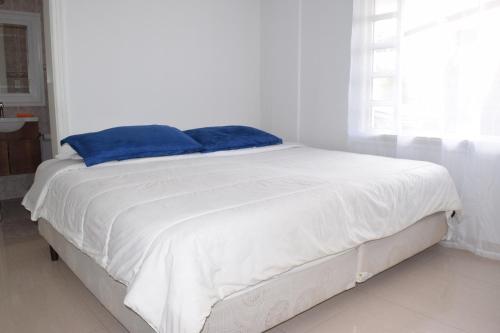 a white bed with blue pillows on top of it at NAPOLES - Luxury Home in Cayambe