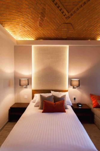 a bedroom with a large white bed with two lamps at Othelo Boutique Hotel Mexico in León